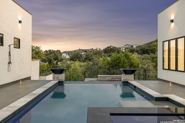 pool at dusk with a patio area