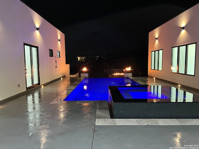 pool at night featuring a patio