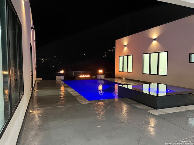 pool at night featuring a patio