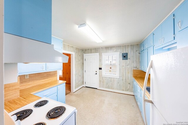 kitchen featuring white refrigerator, wood walls, stove, and blue cabinets