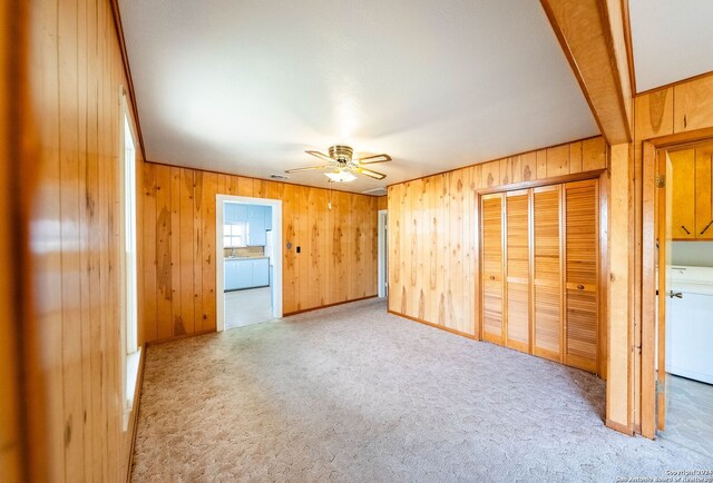 unfurnished bedroom with carpet flooring, wooden walls, and ceiling fan