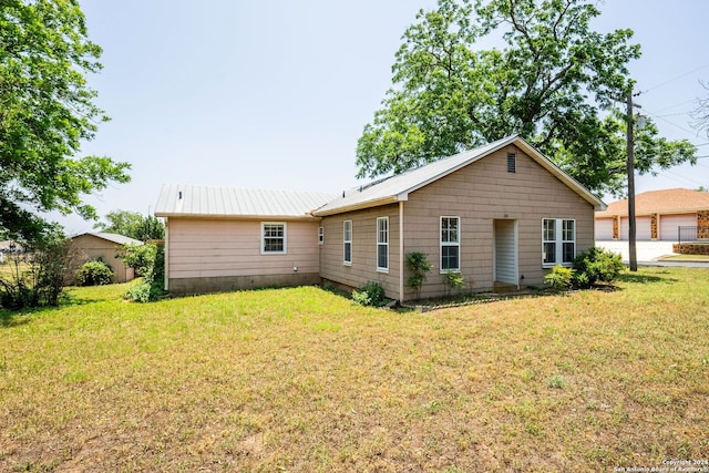 back of property with a garage and a lawn