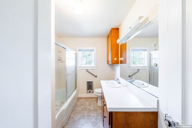 full bathroom with tile flooring, bath / shower combo with glass door, vanity, and toilet