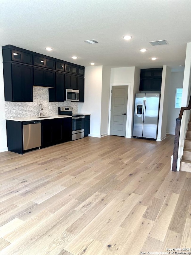 kitchen featuring decorative backsplash, sink, stainless steel appliances, and light hardwood / wood-style flooring