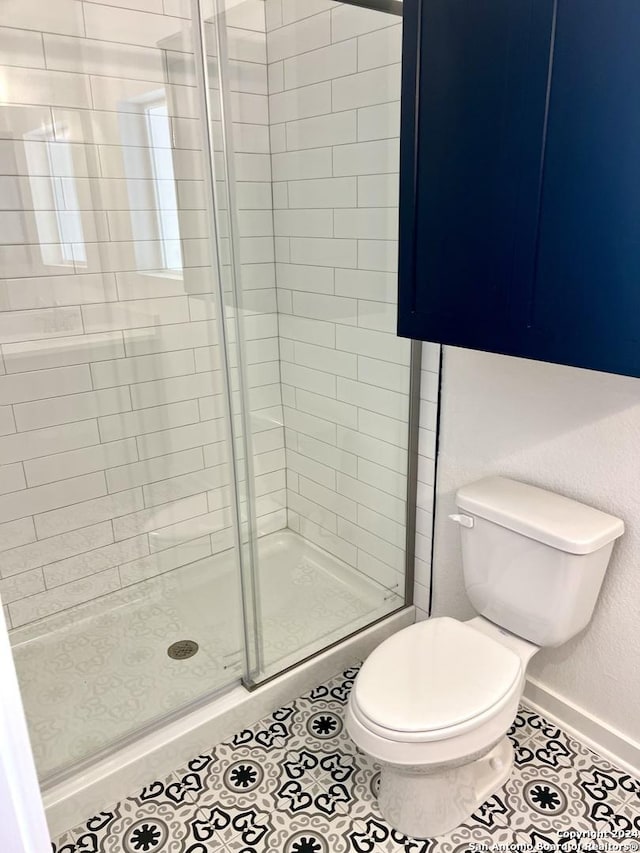 bathroom featuring tile patterned floors, a shower with shower door, and toilet