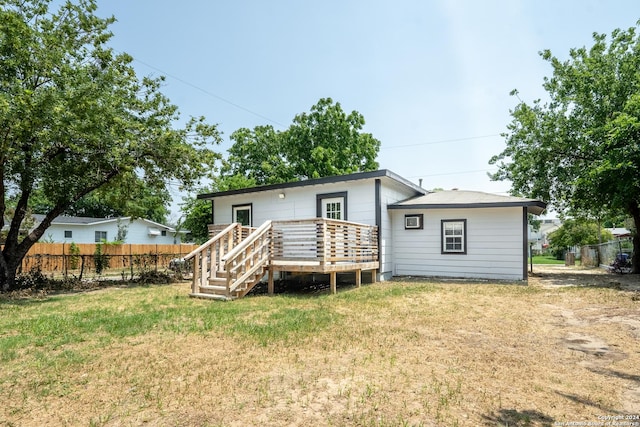 rear view of property with a yard, fence, and a deck