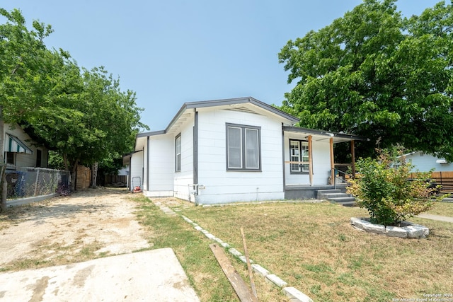 view of front facade with dirt driveway, a porch, a front yard, and fence