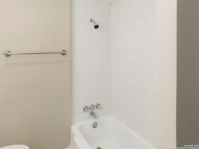 bathroom featuring tiled shower / bath combo and toilet