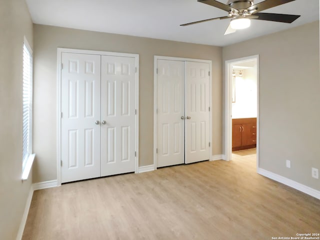 unfurnished bedroom with ceiling fan, light hardwood / wood-style flooring, and multiple closets