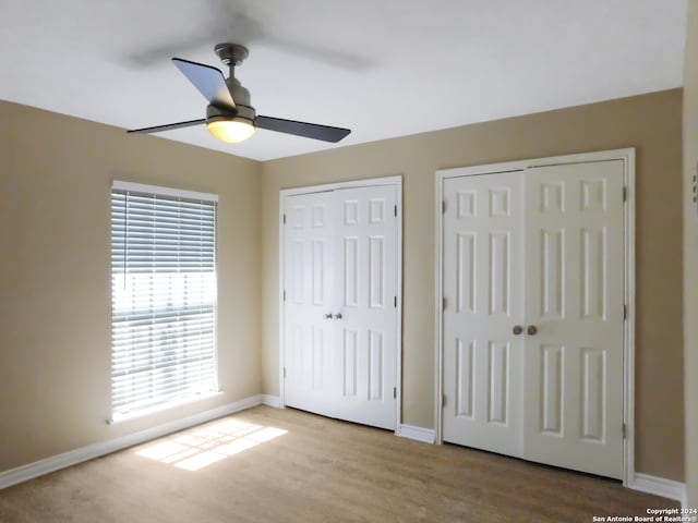 unfurnished bedroom featuring ceiling fan, light hardwood / wood-style flooring, and two closets