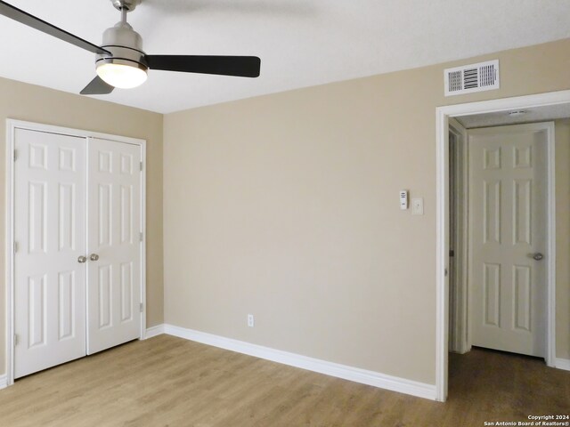 unfurnished bedroom featuring a closet, light hardwood / wood-style flooring, and ceiling fan