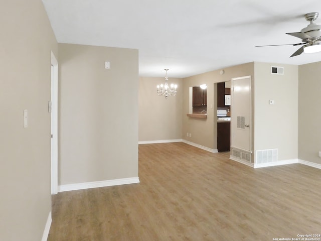 unfurnished room featuring ceiling fan with notable chandelier and light hardwood / wood-style flooring