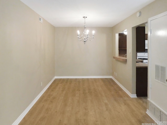 unfurnished dining area with light hardwood / wood-style floors and a notable chandelier