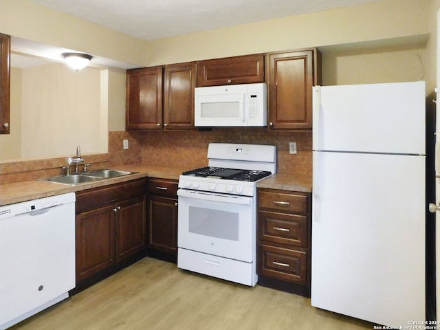 kitchen with light wood-type flooring, white appliances, tasteful backsplash, and sink