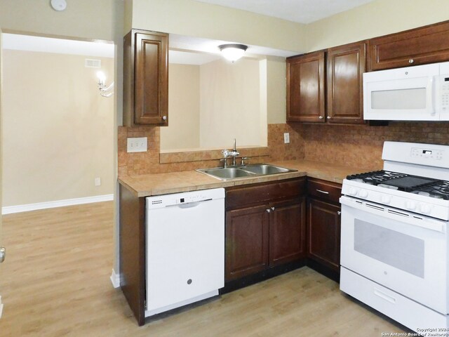 kitchen featuring tasteful backsplash, light hardwood / wood-style flooring, and white appliances