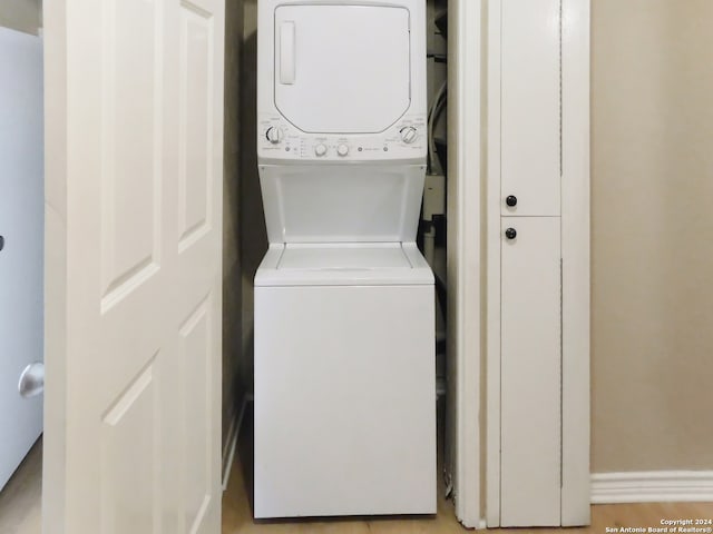 clothes washing area with stacked washing maching and dryer