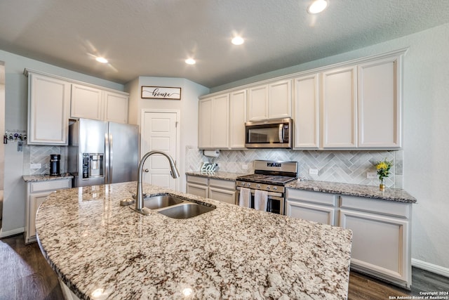 kitchen featuring a center island with sink, white cabinets, sink, appliances with stainless steel finishes, and dark hardwood / wood-style flooring