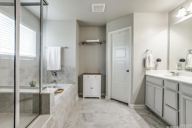 bathroom with vanity and a relaxing tiled tub