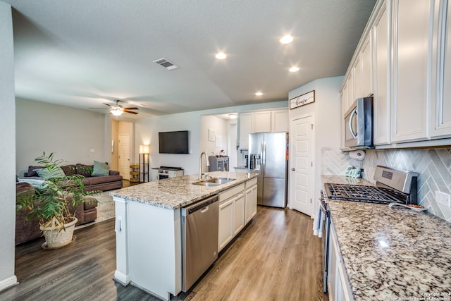 kitchen featuring appliances with stainless steel finishes, light wood-type flooring, a kitchen island with sink, sink, and white cabinets