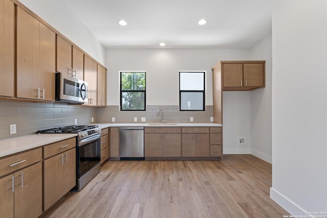 kitchen with decorative backsplash, sink, stainless steel appliances, and light hardwood / wood-style flooring