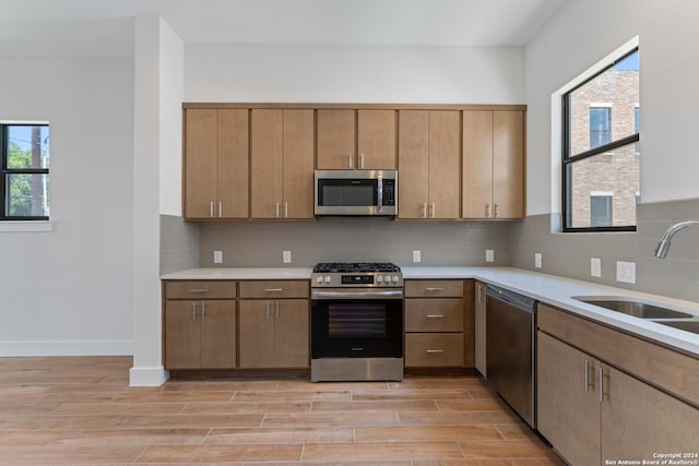 kitchen with stainless steel appliances, light hardwood / wood-style flooring, plenty of natural light, and sink