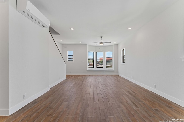 unfurnished living room featuring ceiling fan, dark hardwood / wood-style flooring, and a wall mounted AC