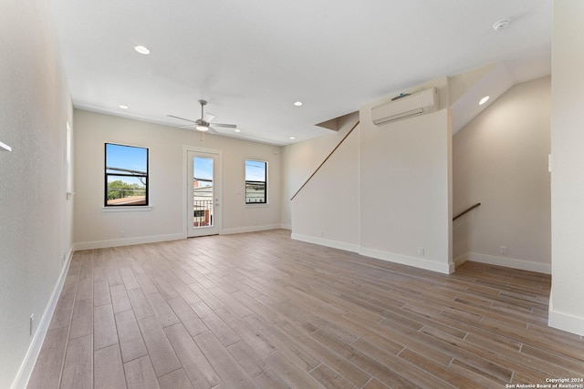 unfurnished living room with light hardwood / wood-style floors, a wall unit AC, and ceiling fan