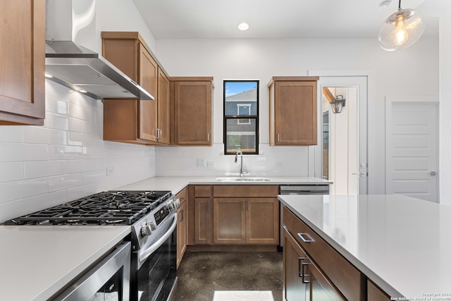 kitchen with wall chimney range hood, stainless steel gas range, pendant lighting, sink, and tasteful backsplash