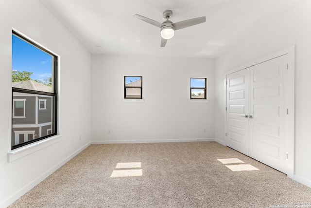 unfurnished bedroom with carpet flooring, a closet, ceiling fan, and multiple windows