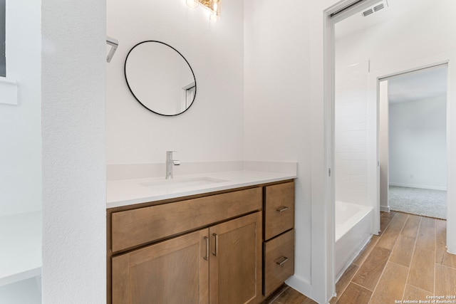 bathroom featuring hardwood / wood-style floors, vanity, and bathing tub / shower combination