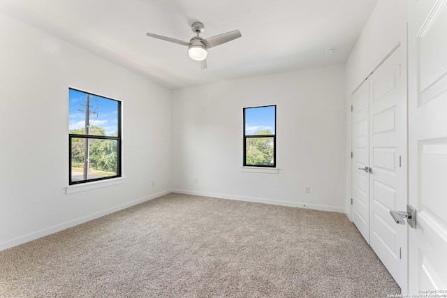 unfurnished bedroom with a closet, carpet, multiple windows, and ceiling fan