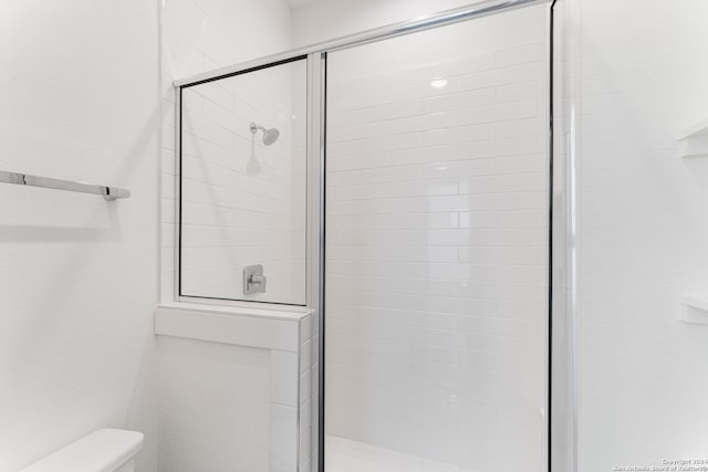 bathroom featuring an enclosed shower and toilet