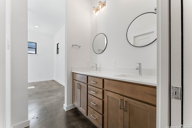 bathroom featuring large vanity, double sink, and concrete flooring