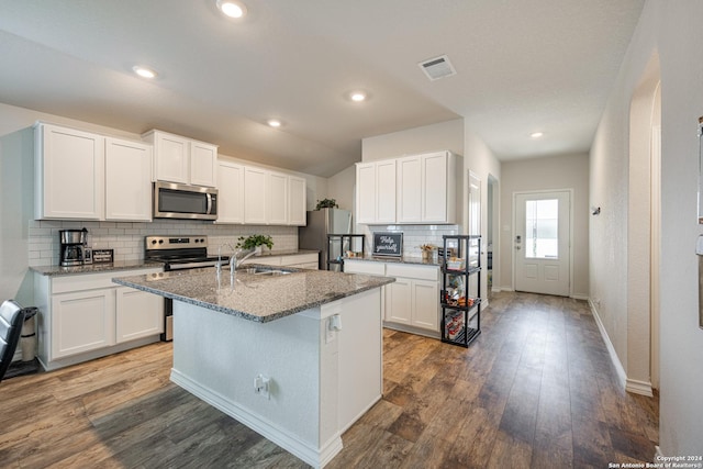 kitchen featuring appliances with stainless steel finishes, a center island with sink, stone countertops, dark hardwood / wood-style floors, and white cabinetry