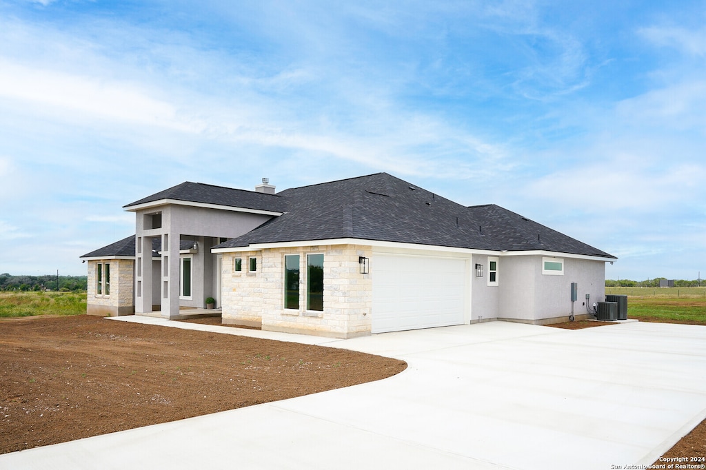 rear view of property with a garage and cooling unit