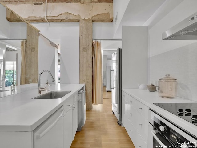 kitchen with wall chimney exhaust hood, stainless steel appliances, sink, light hardwood / wood-style flooring, and white cabinetry