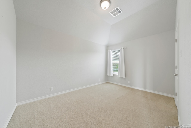 spare room featuring light colored carpet and lofted ceiling