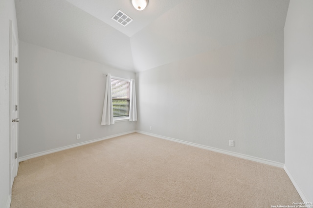 carpeted empty room with vaulted ceiling