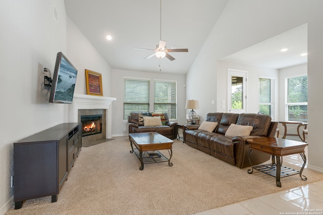 carpeted living room featuring a tile fireplace, ceiling fan, and high vaulted ceiling