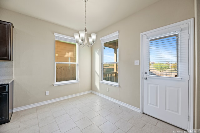 unfurnished dining area with a notable chandelier and light tile patterned flooring