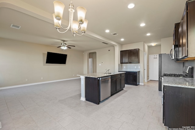 kitchen with pendant lighting, a center island with sink, ceiling fan with notable chandelier, sink, and appliances with stainless steel finishes