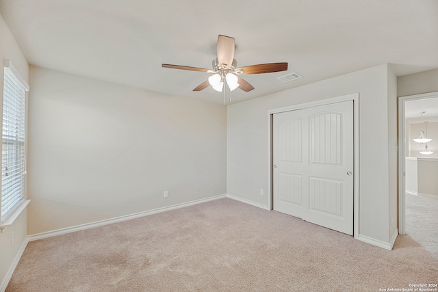 unfurnished bedroom featuring a closet, light colored carpet, and ceiling fan