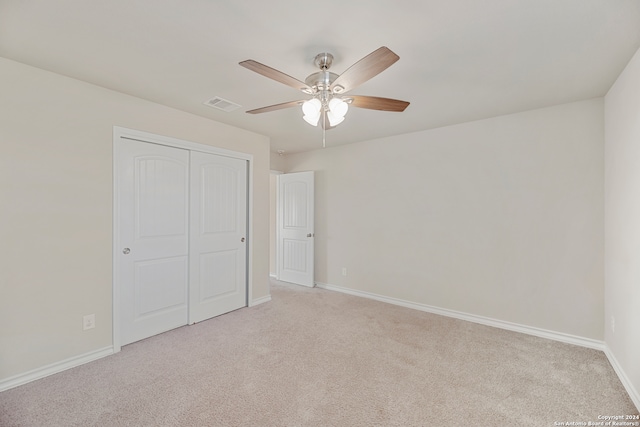 unfurnished bedroom featuring ceiling fan, light carpet, and a closet