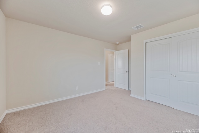 unfurnished bedroom featuring light carpet and a closet