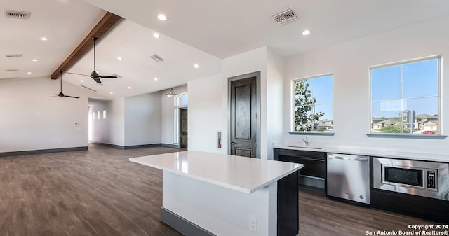 kitchen with beamed ceiling, appliances with stainless steel finishes, a center island, and dark wood-type flooring