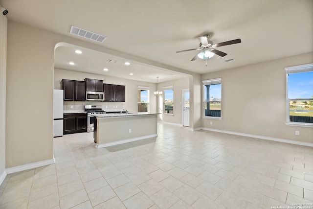 kitchen with appliances with stainless steel finishes, light tile patterned floors, plenty of natural light, and a kitchen island with sink