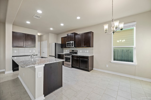 kitchen featuring sink, stainless steel appliances, decorative backsplash, a kitchen island with sink, and dark brown cabinets