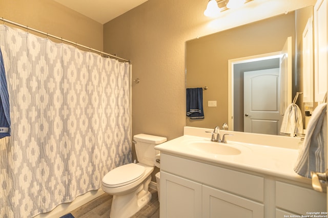 bathroom with vanity with extensive cabinet space, toilet, and wood-type flooring