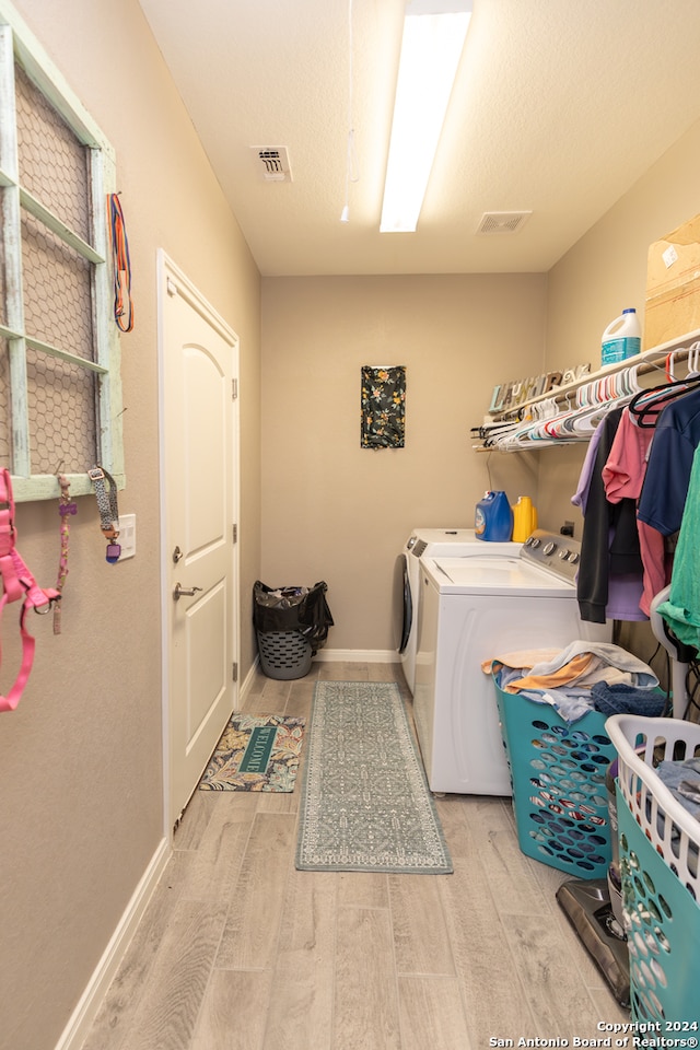 washroom with washing machine and dryer and light wood-type flooring