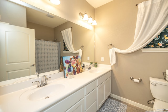 bathroom featuring dual sinks, toilet, and large vanity